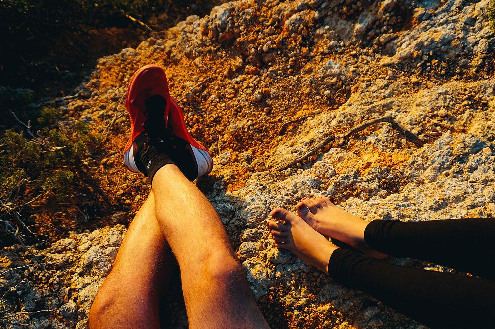 Feet of man and woman against rocks during sunset hour at cliffs