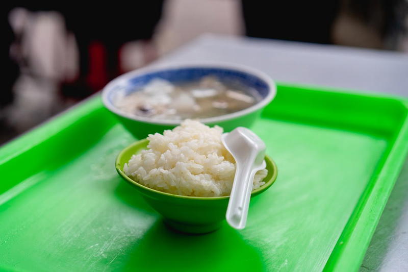 Two bowls of rice and a spoon on a green tray.