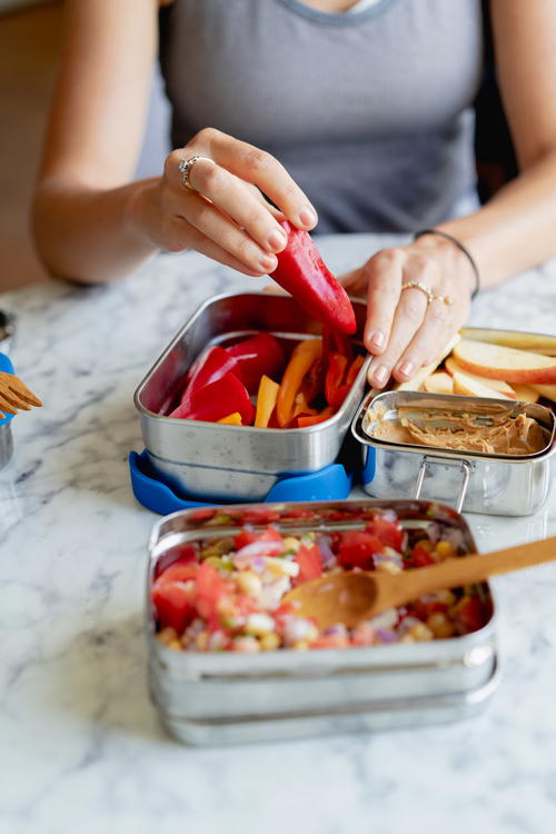 A woman is preparing food in a lunch box.