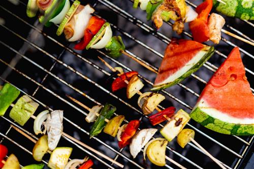 Skewers of vegetables and watermelon on a grill.