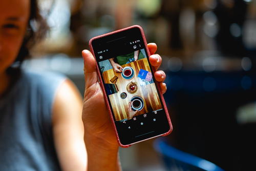 A woman holding up a cell phone with a picture on it.