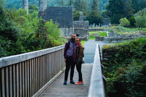 A couple standing on a wooden bridge in ireland.