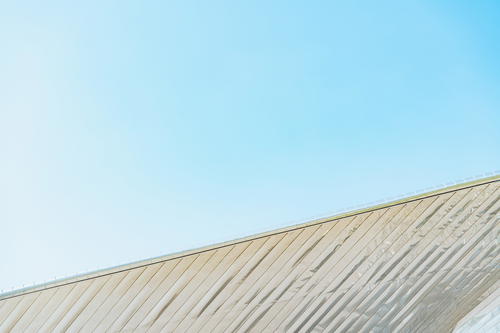 A man is riding a skateboard against a blue sky.