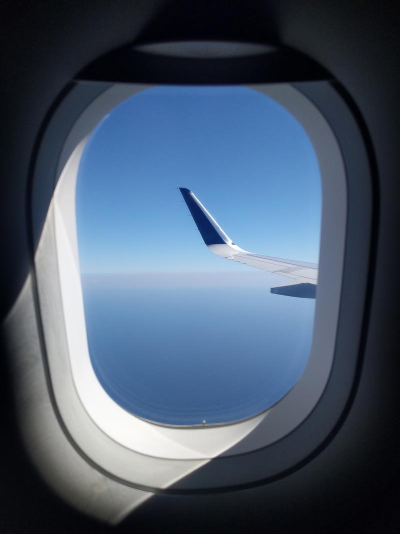 An airplane window with a view of the sky.