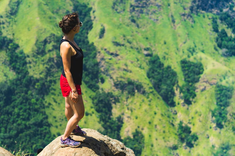 A woman standing on top of a mountain overlooking a valley.