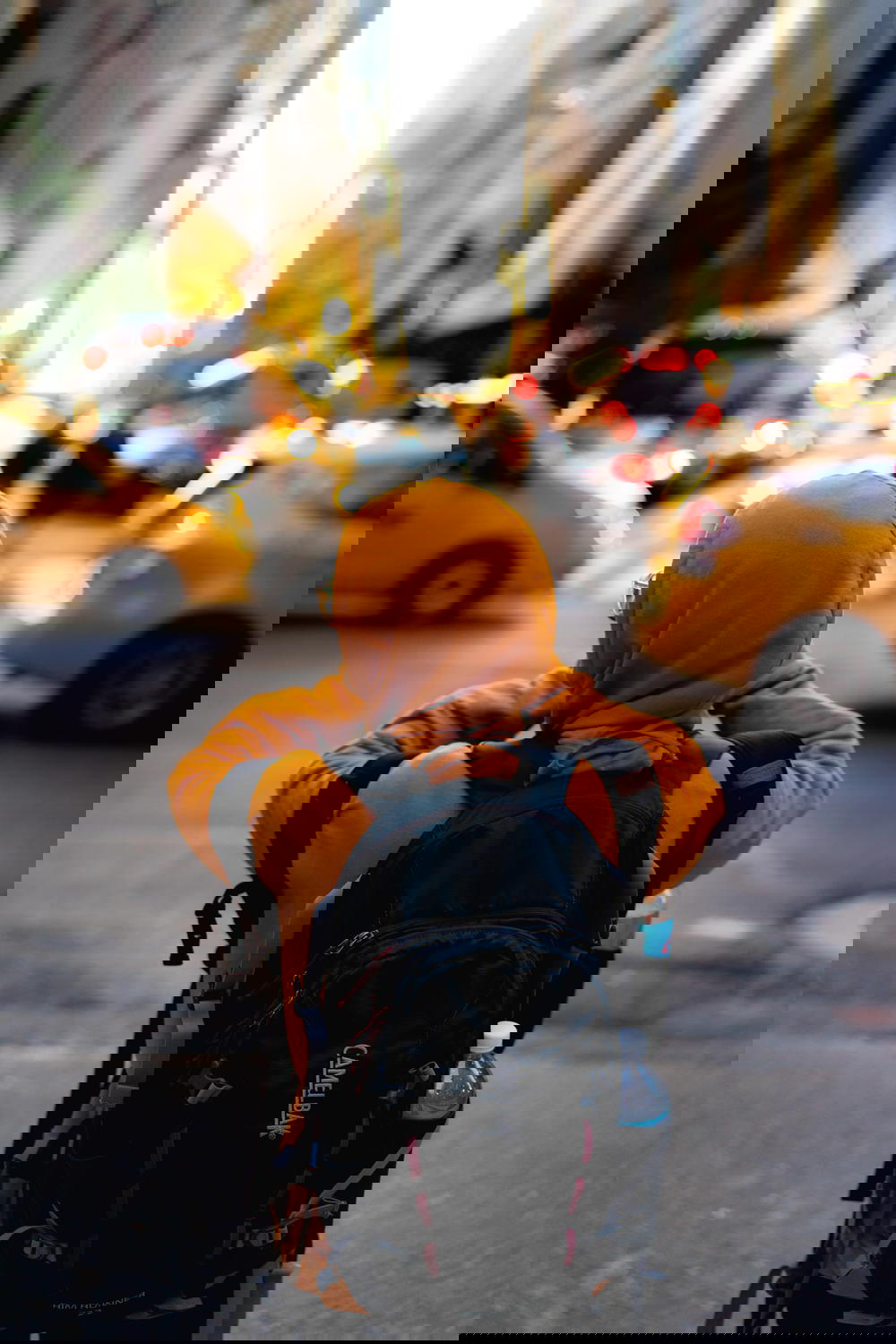 Girl in yellow sweatshirt with a backpack during sunset in New York City