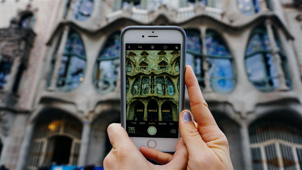 A person capturing the beauty of a Barcelona building through photography in Spain.