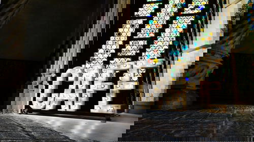 Large lit-up letters CAFE next to a stained glass window inside