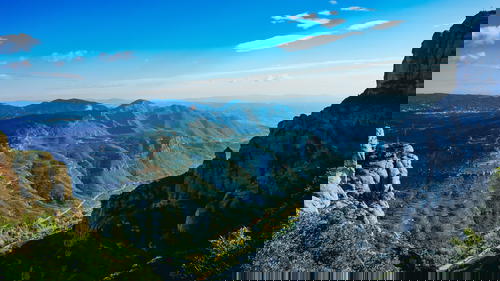 Blue and green expanse of mountains with winding roads in a valley