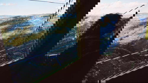 Woman looking through the windows of a yellow gondola going down a mountain