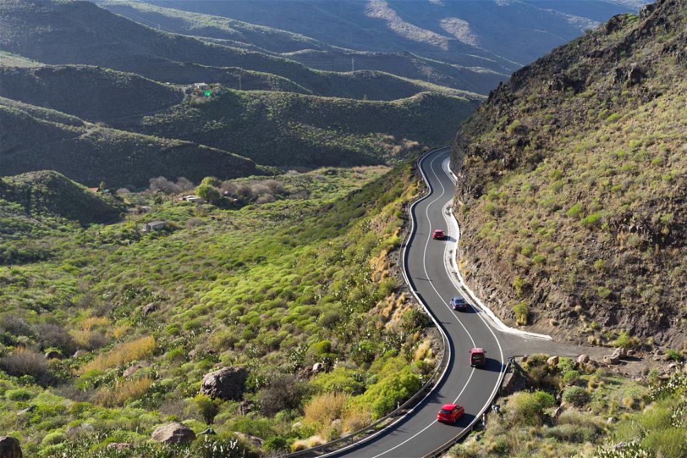 Two cars driving down a winding road in the mountains of Spain.