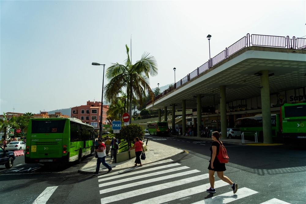 People crossing the street at a crosswalk near bus station