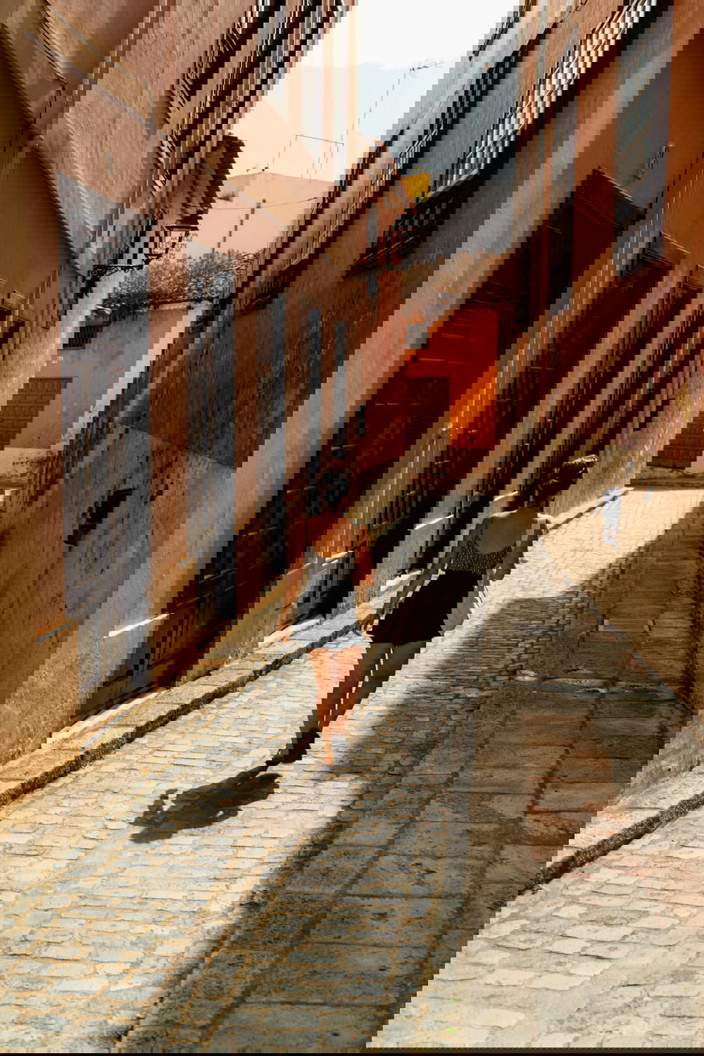 Woman walking in narrow alley between painted Spanish walls