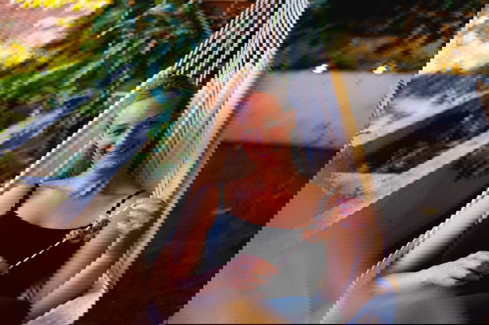 A woman enjoying the Tenerife scenery while indulging in food at a Nine Coliving hammock.