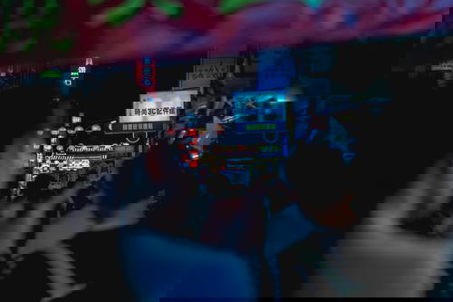 A blurry image of people walking down a street in Taipei, Taiwan at night.