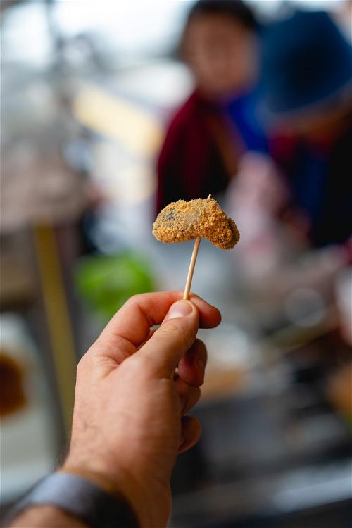 Holding up rice street food on a toothpick in a food market in Taipei Taiwan