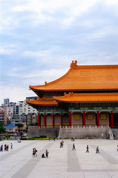National Concert Hall of Taiwan's orange tiled roof and red column architecture with people walking in a plaza
