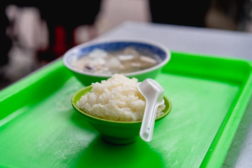 Bowl of fluffy white rice with a white spoon in a green bowl