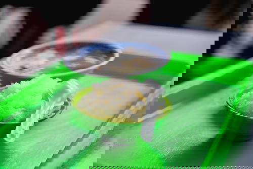 Bowl of fluffy white rice with a white spoon in a green bowl