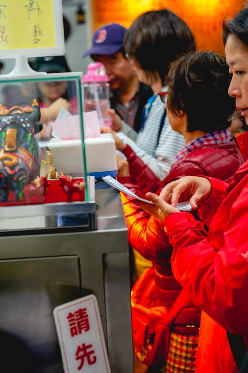 Taiwanese people waiting on line for street food at a metal stall in a market