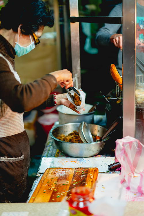 Street vendor placing fried chicken into a white bag for sale in Taipei