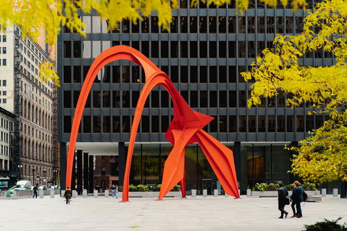 A large red sculpture in the middle of a square.
