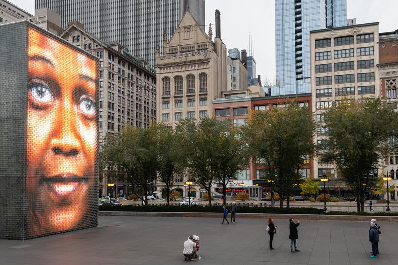 A large screen showing a woman's face in the middle of a city.