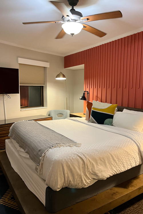 A bed in a Chicago room with a ceiling fan.