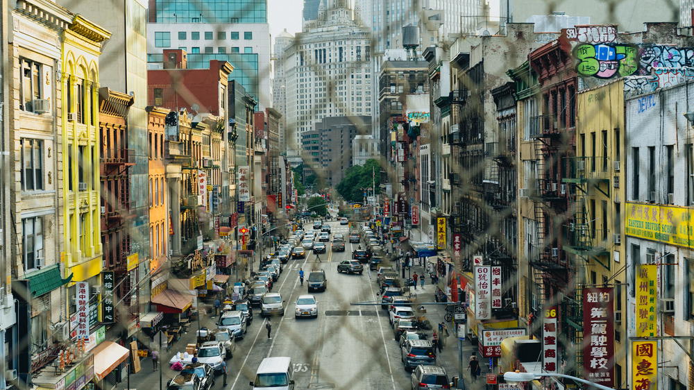 A view of a city street near the Manhattan Bridge from a fence.