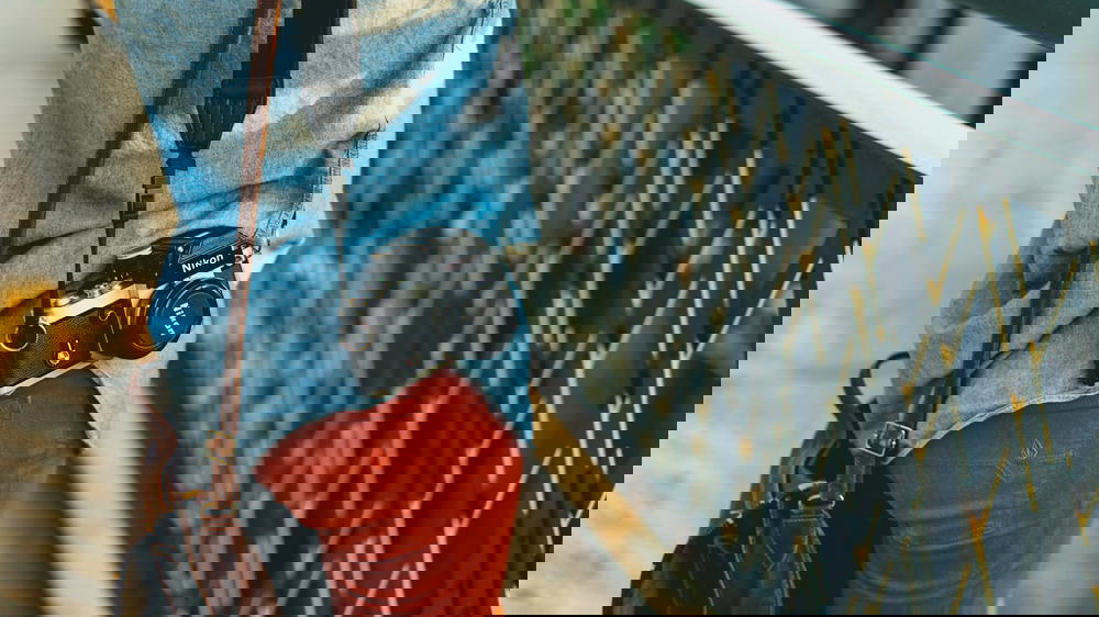 Person with blue shirt and red pants with a vintage Nikon film camera