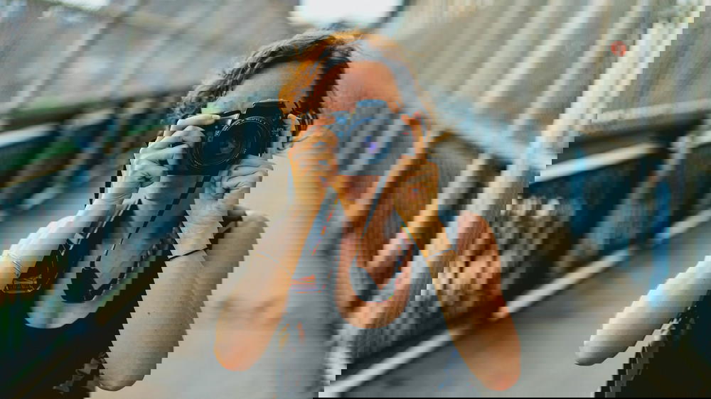 Woman taking a photo with a Canon camera on the Manhattan Bridge