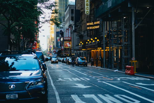 A car is parked on a city street in NYC's Times Square.