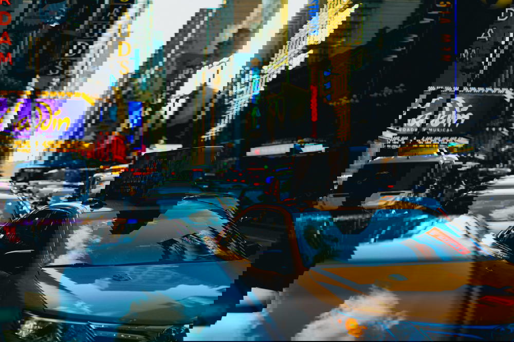 A yellow taxi parked on a city street in Times Square, NYC.