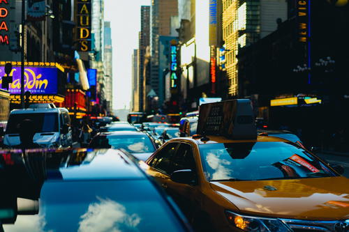 A yellow taxi parked on a city street in Times Square, NYC.