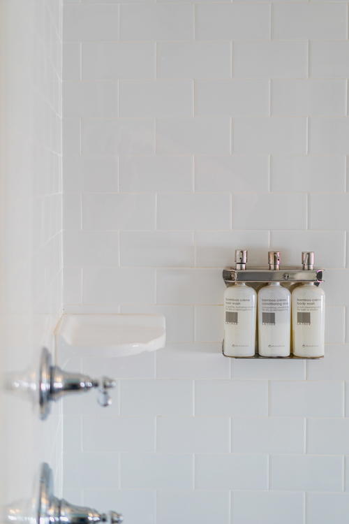 A white tiled shower in Hotel on North with a soap dispenser on the wall.