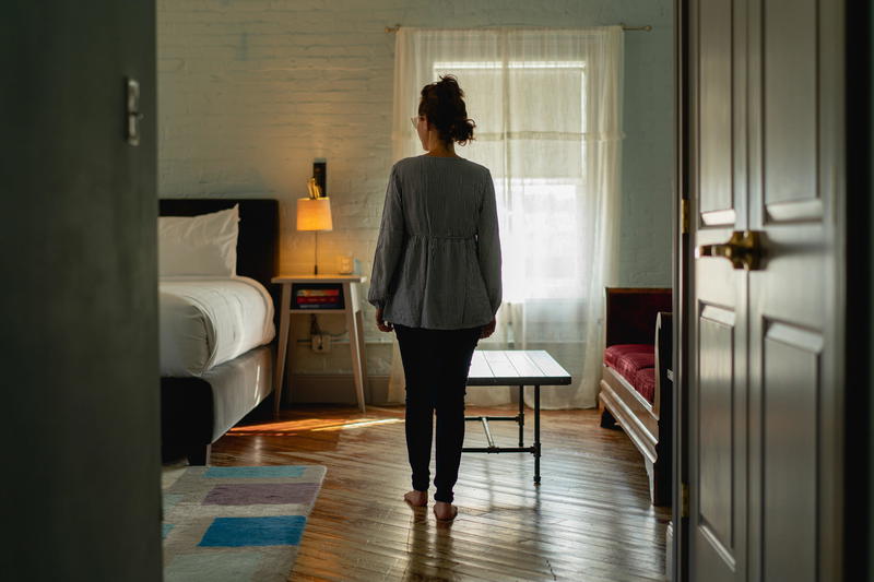 A woman in Pittsfield Massachusetts standing in front of a bed in Hotel on North.