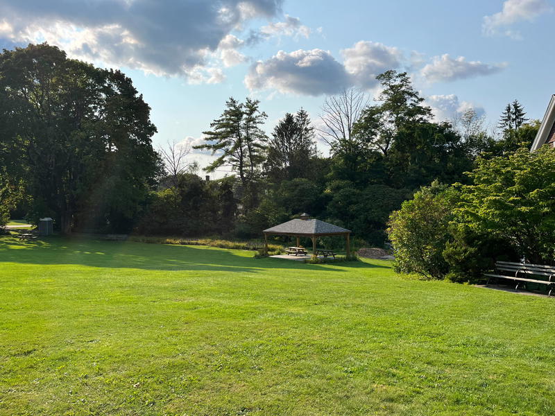 A large grassy area in Massachusetts with a gazebo and benches.