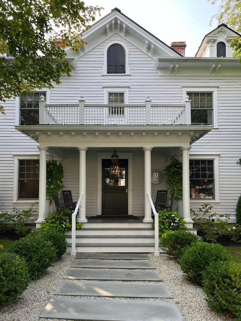 A white Massachusetts house with a porch and steps in Lenox.