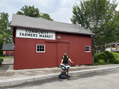 A man standing in front of a red building at the community farmers market in Litchfield, Connecticut.