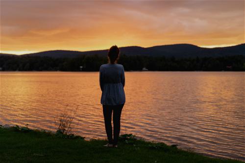 A woman standing by a lake at sunset in Pittsfield, Massachusetts.