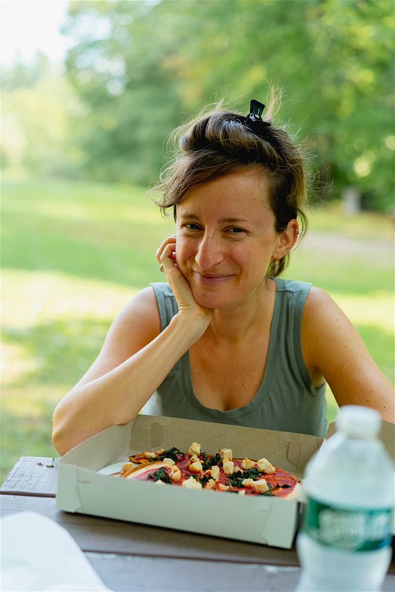 A woman enjoying a pizza at a picnic table in Pittsfield, Massachusetts.
