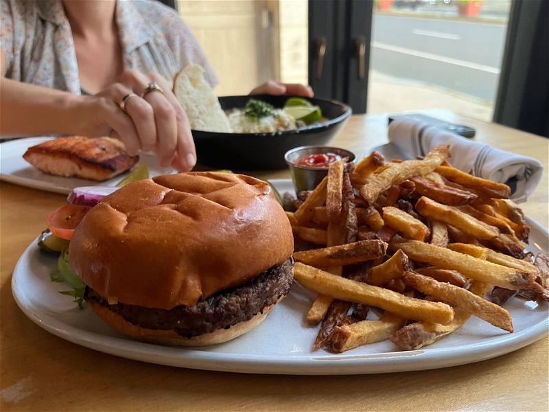 A woman is enjoying a burger and fries at a restaurant in Pittsfield, Massachusetts.