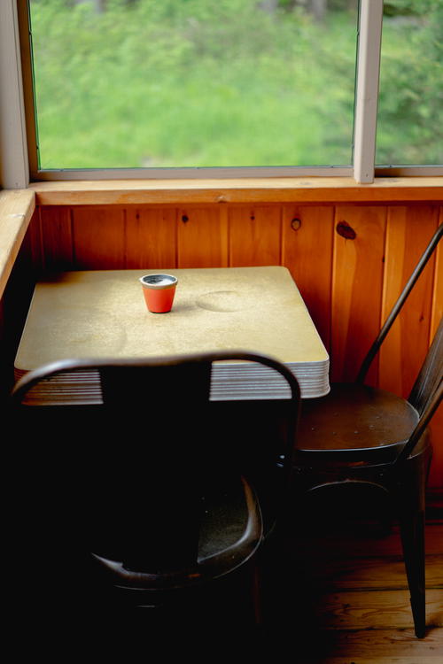 A table and chairs in front of a window overlooking Antrim Streamside in the Catskills of New York.