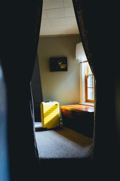 A Beacon room with a yellow suitcase and a window.