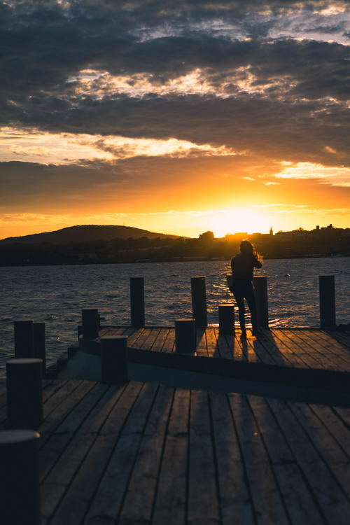 A person sitting on a dock in Beacon, New York at sunset.