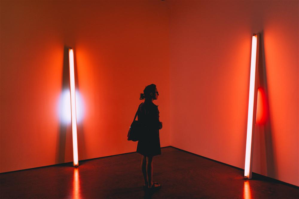 A woman stands in a Beacon, New York room illuminated by red and orange lights.