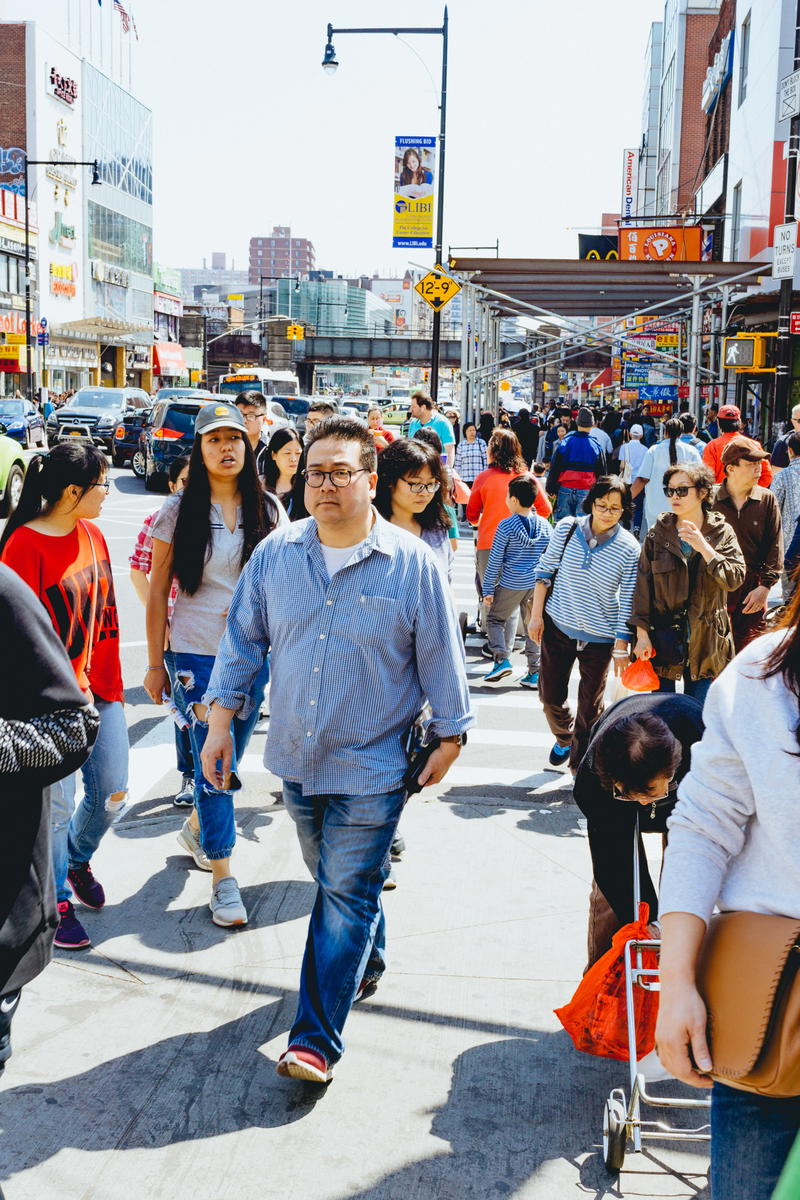 A group of people walking on a sidewalk in NYC.