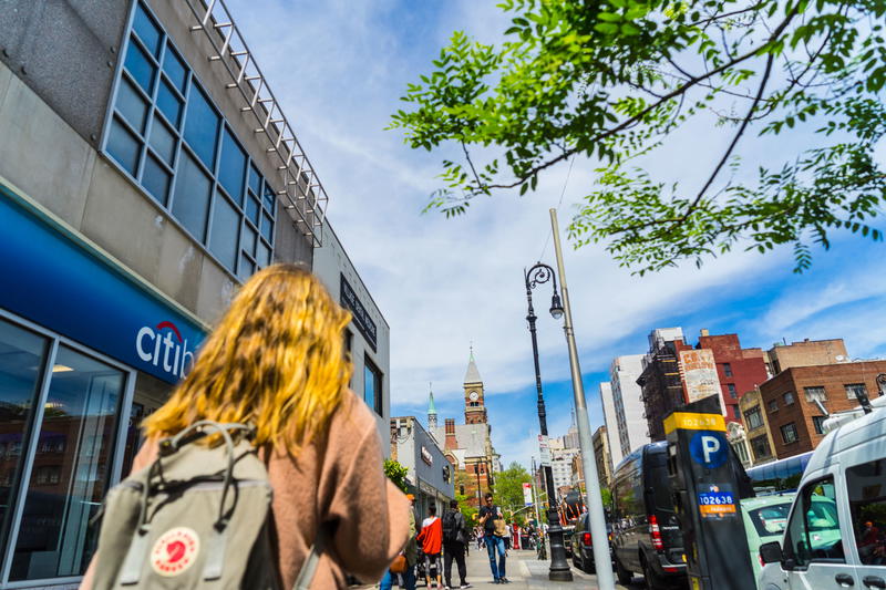 A woman wandering through NYC streets with a backpack.