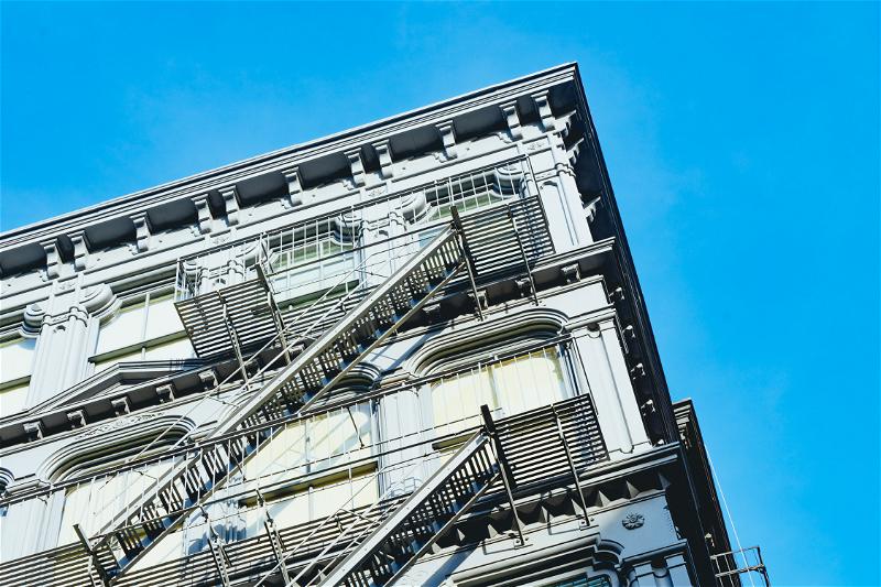 A gray building with visible fire escapes in the SoHo neighborhood of NYC