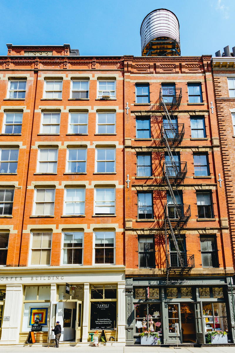 A 6 story walk-up style building in SoHo with a water tower and fire escapes